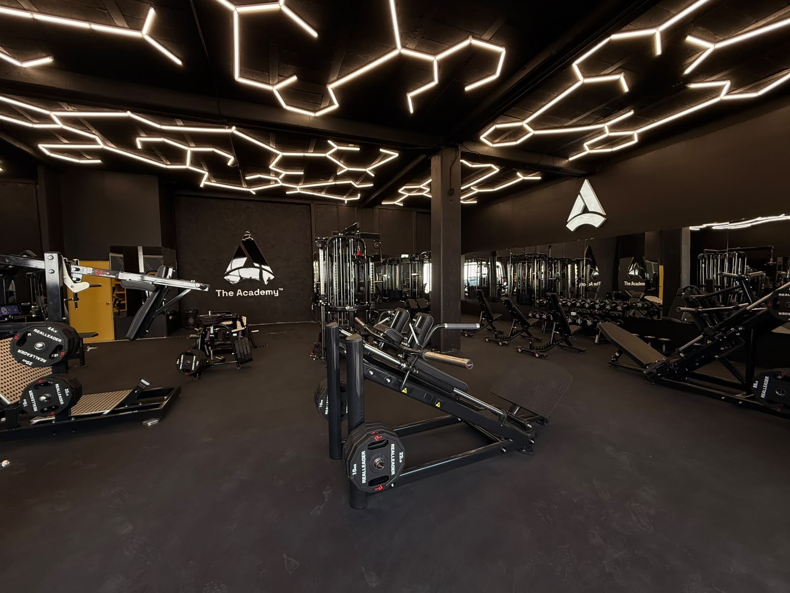 Interior de The Academy Human Strength Center con iluminación hexagonal y equipo profesional